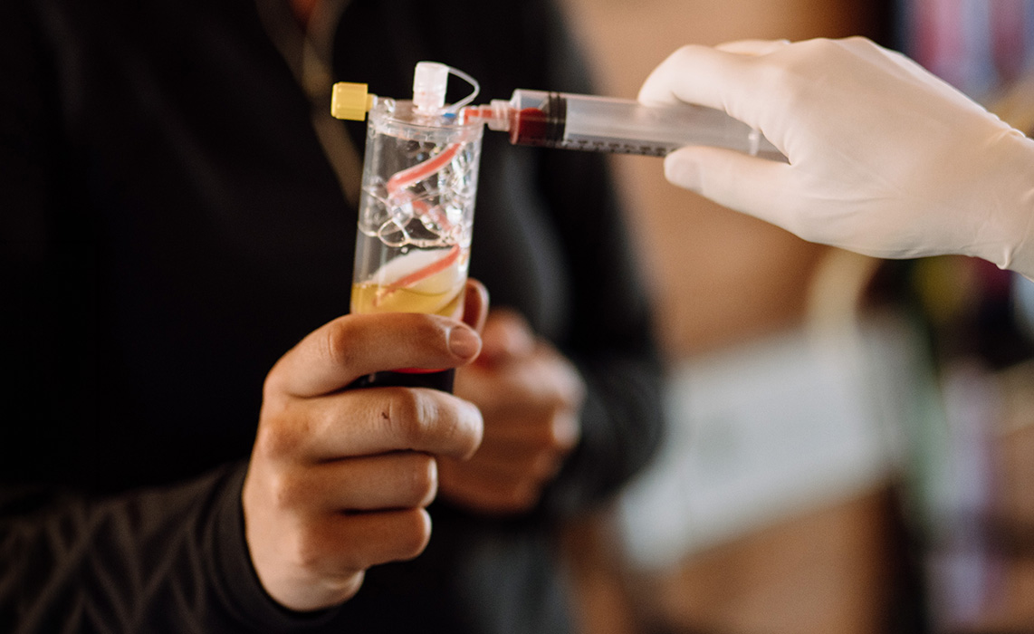 Gloved veterinary professional preparing a blood-derived regenerative medicine product.